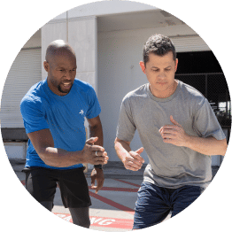 personal trainer wearing a blue tshirt directing a client outdoors located on the ace fitness personal trainer certification webpage